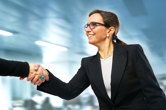 Business woman greeting a visit to her office with a handshake