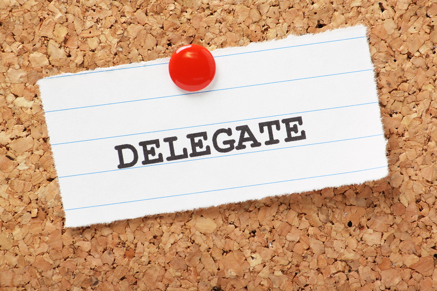 The word Delegate typed onto a scrap of lined paper and pinned to a cork notice board. Knowing when to delegate to others is an essential skill in leadership and time management.