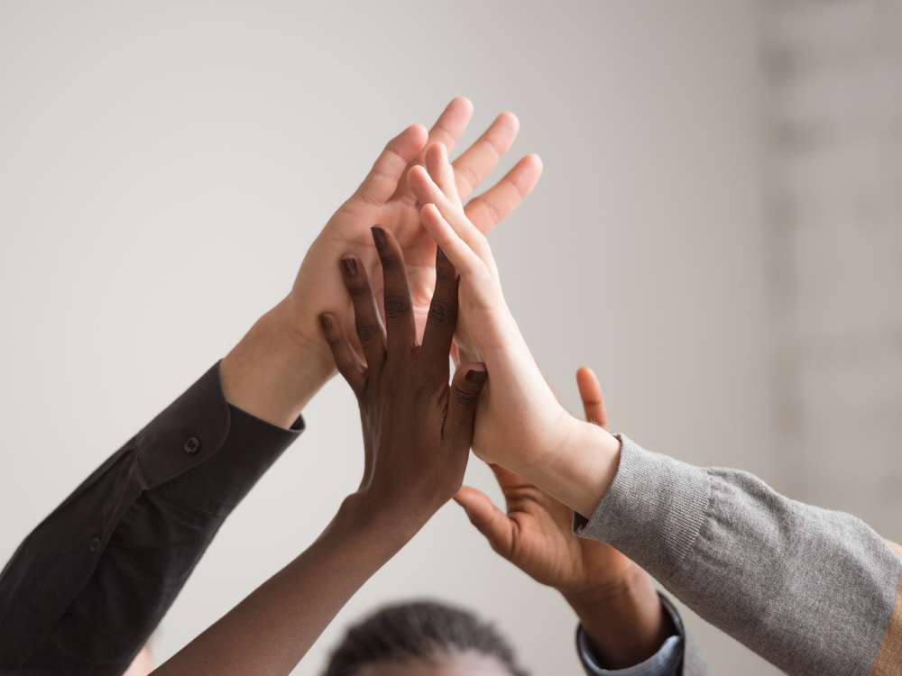 a group of people putting their hands together for support